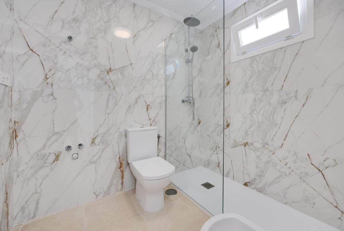 Modern, elegant bathroom with glass shower and marble walls in a 3-bedroom villa in El Oasis, San Fulgencio.