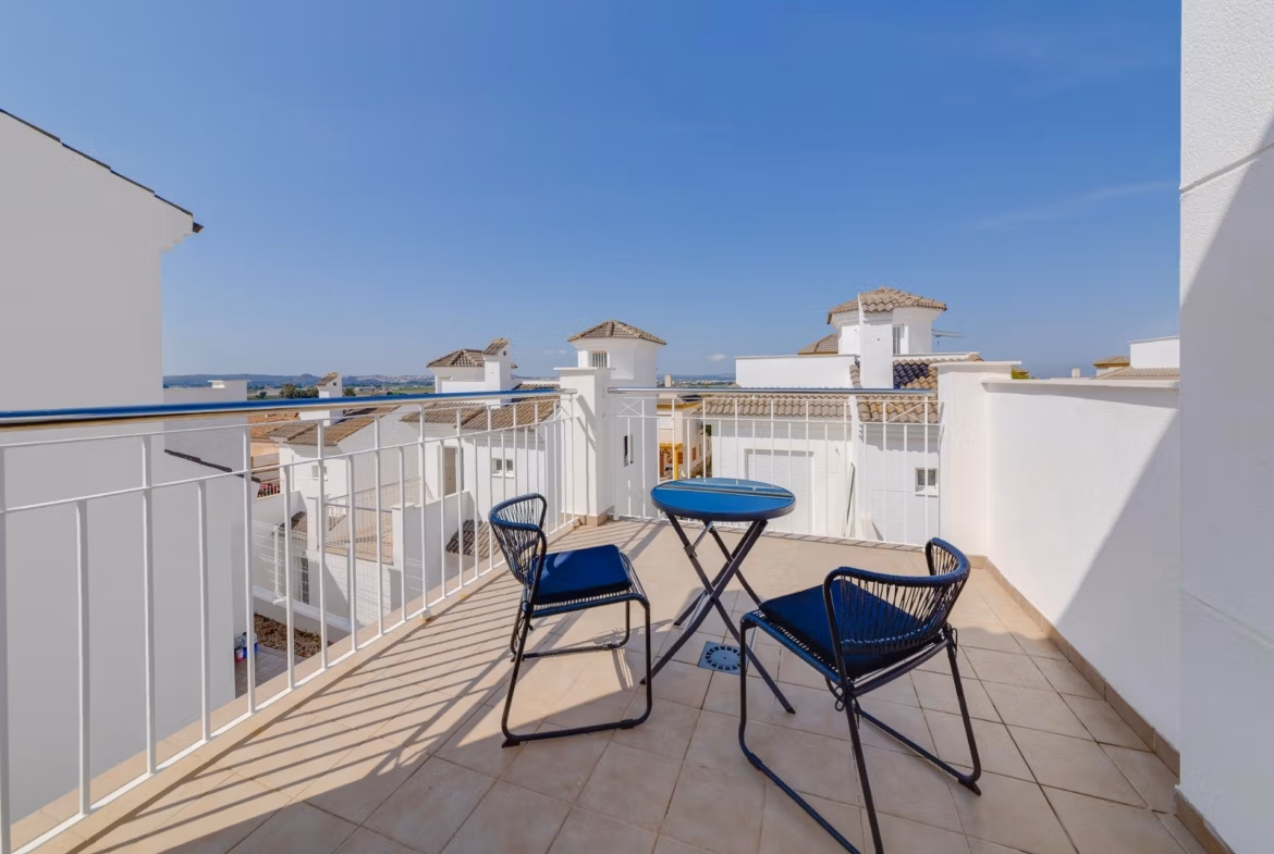 Sunlit solarium terrace with sleek black chairs and table, overlooking whitewashed rooftops of a 3-bedroom villa in El Oasis, San Fulgencio.