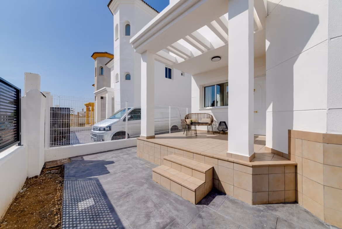 NEW-BUILD-RESIDENTIAL-IN-SAN-FULGENCIO-32 Bright and modern porch of a 2 bedroom semi-detached villa in El Oasis La Marina Urbanisation with tiled steps and outdoor seating.