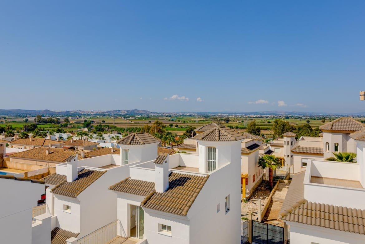 Sunlit exterior view of modern 3 bedroom villas with tiled roofs surrounded by landscaped gardens in El Oasis, San Fulgencio.
