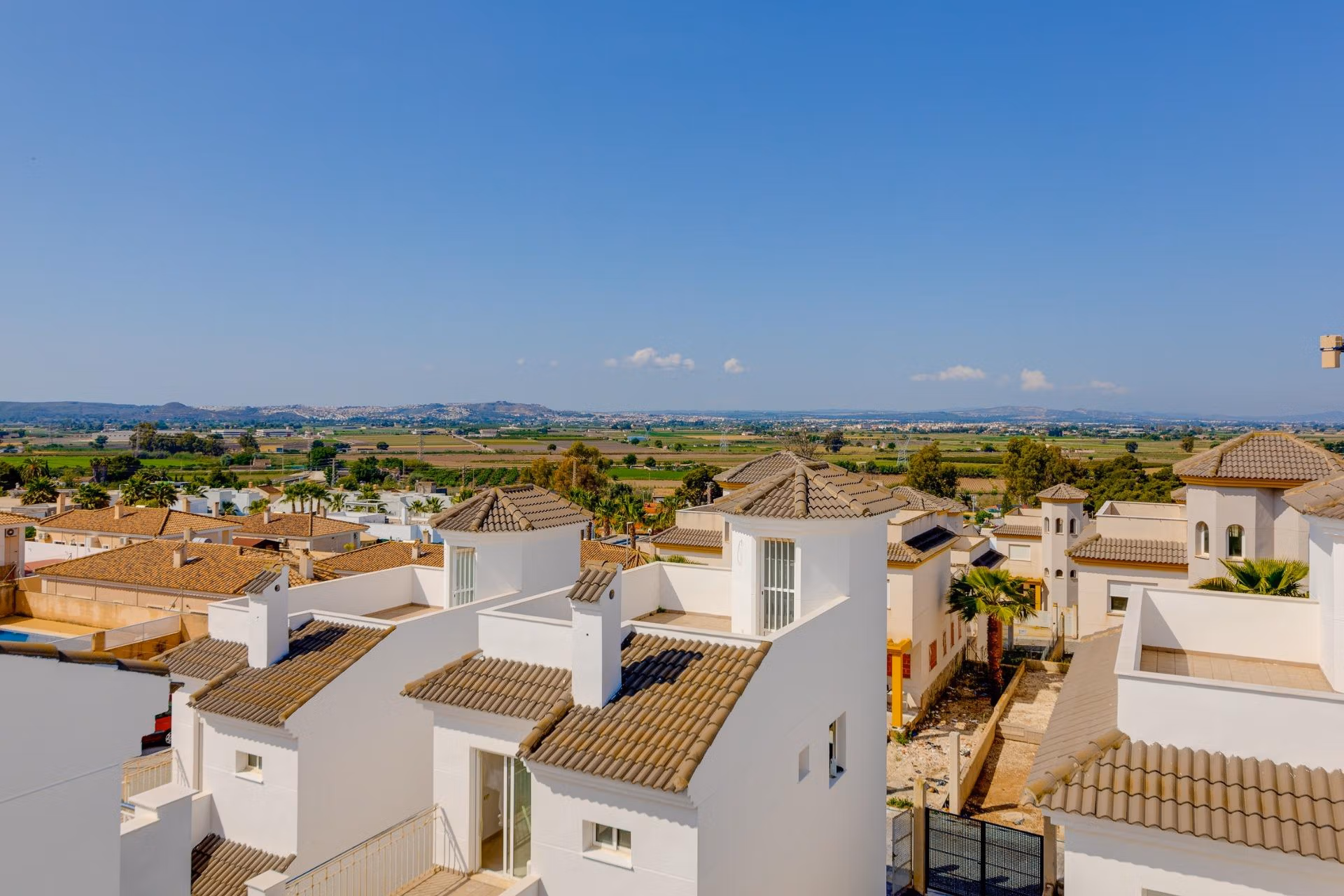 NEW-BUILD-RESIDENTIAL-IN-SAN-FULGENCIO-34 Sunlit exterior view of modern 3 bedroom villas with tiled roofs surrounded by landscaped gardens in El Oasis, San Fulgencio.