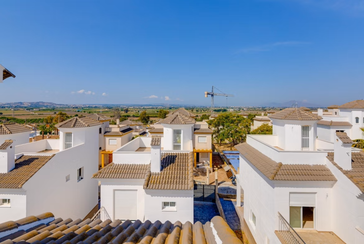 NEW-BUILD-RESIDENTIAL-IN-SAN-FULGENCIO-35 Sun-drenched exterior of key ready 2 bedroom semi-detached villas in El Oasis La Marina Urbanisation with panoramic views and tiled roofs.