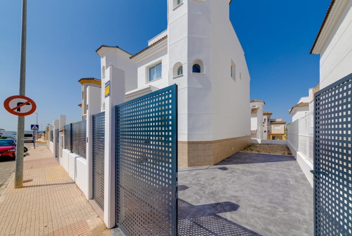 Modern white 3 bedroom villa exterior with gated entrance and clear blue sky in El Oasis, San Fulgencio.