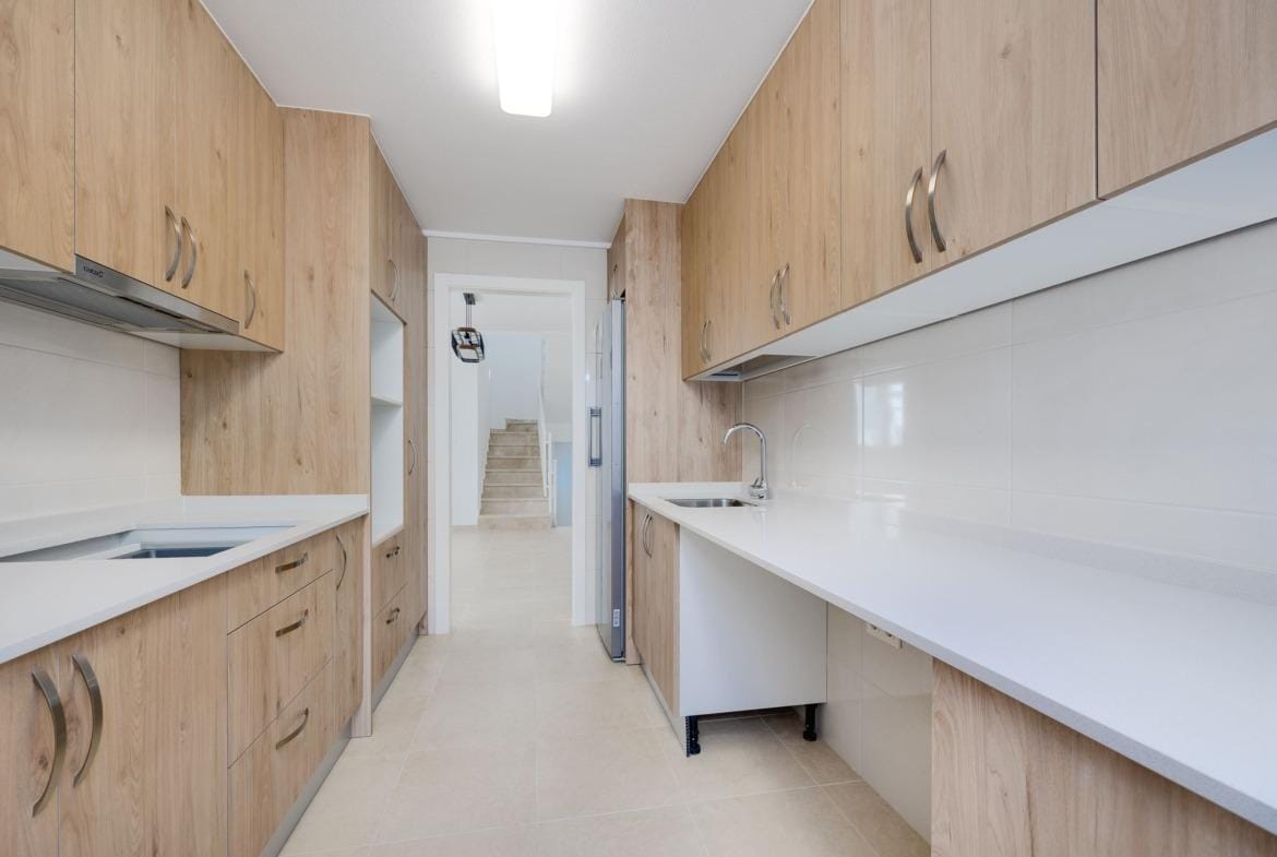 Modern, bright kitchen with sleek wood cabinetry in a key ready 3 bedroom villa in El Oasis, San Fulgencio.