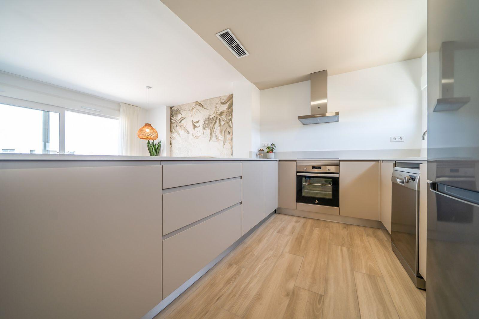 NEW-BUILD-RESIDENTIAL-OF-BUNGALOW-APARTMENTS-IN-VISTABELLA-10 Bright modern kitchen with sleek cabinetry and wood flooring in a 2 bedroom top floor bungalow in Vistabella Golf, Orihuela.