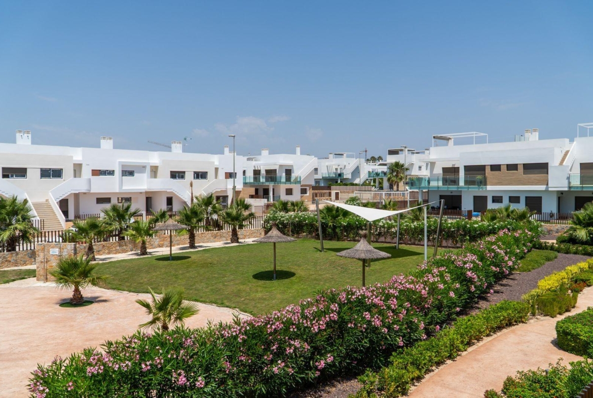 Modern 2-bedroom townhouse exterior with lush landscaped garden and communal green spaces in Vistabella Golf, Orihuela.