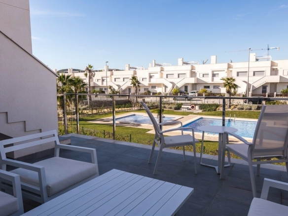 Spacious terrace overlooking the pristine pool and landscaped gardens in a modern 2-bedroom top floor apartment at Vistabella Golf, Orihuela.