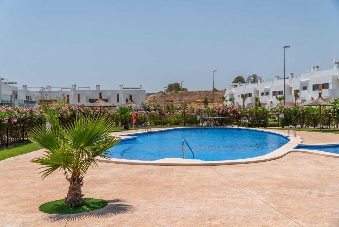 Sun-drenched communal pool with landscaped gardens in a modern 2-bedroom townhouse complex at Vistabella Golf, Orihuela.