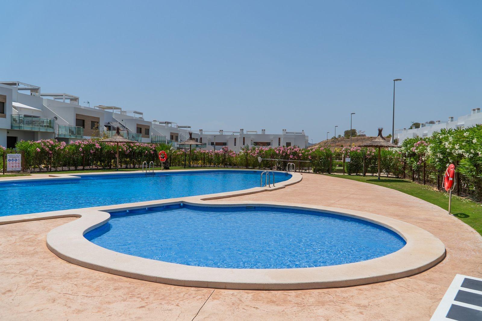 Sun-drenched communal pool with landscaped gardens surrounding modern new build 2 bedroom townhouses in Vistabella Golf, Orihuela.
