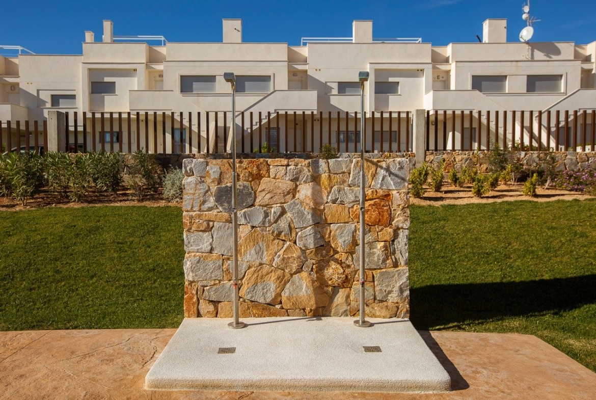 Modern outdoor shower area with natural stone wall and landscaped garden in luxury 2-bedroom top floor apartment at Vistabella Golf Orihuela