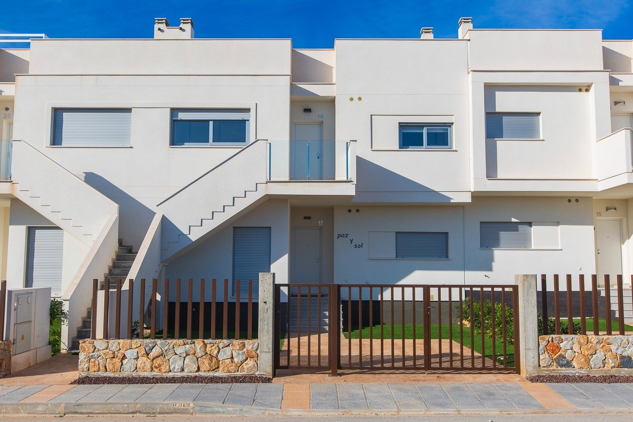 Modern white facade of top floor 2-bedroom apartment with private solarium and gated entrance in Vistabella Golf, Orihuela.