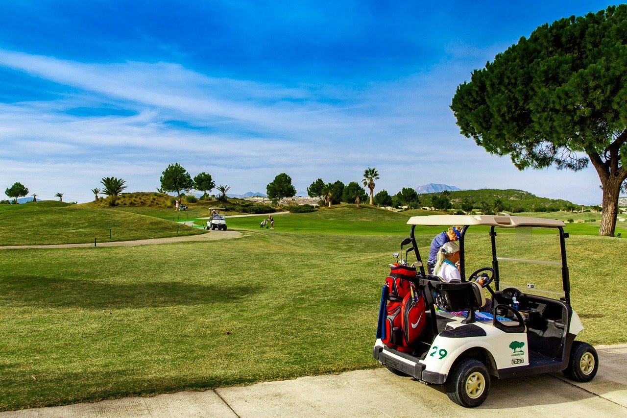 Sunlit golf course view with a modern golf cart, surrounding greenery from the top floor 2-bedroom apartment at Vistabella Golf, Orihuela.