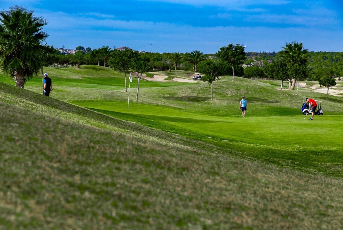 Lush, sunlit golf course with rolling greens and palm trees near the new build 2 bedroom apartment in Vistabella Golf, Orihuela.