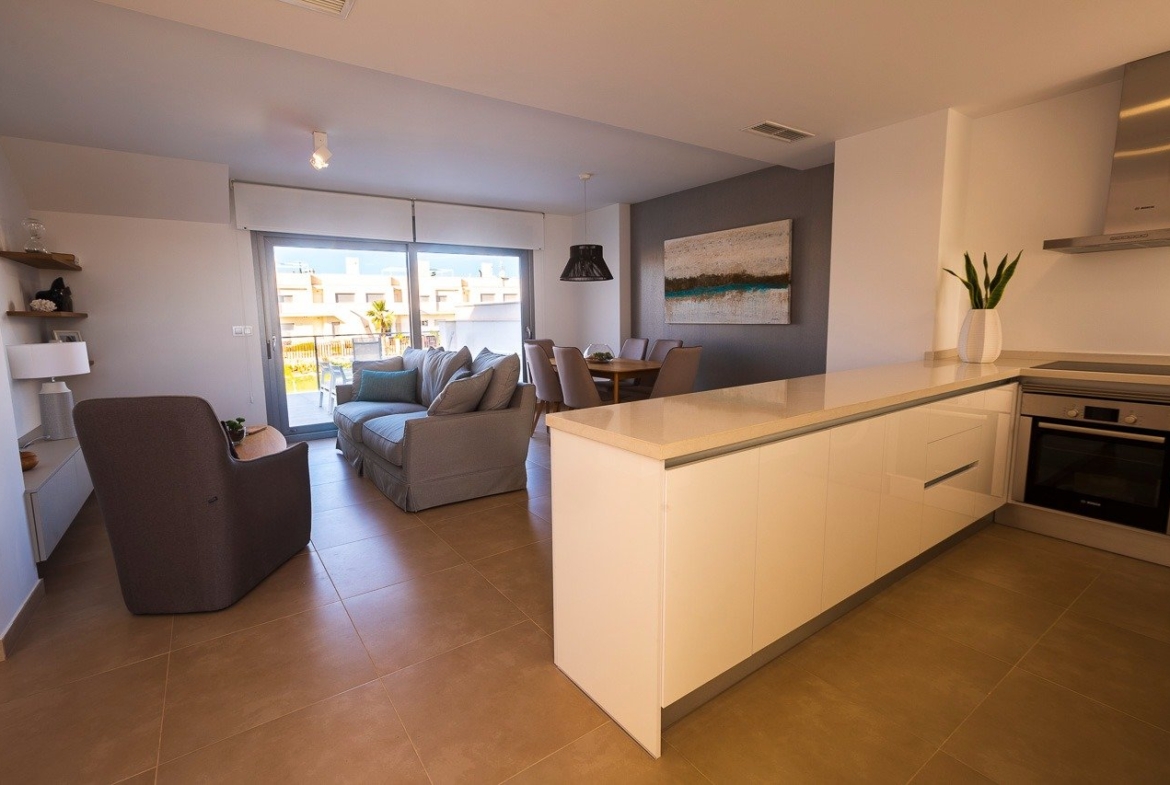 Sun-drenched open-plan kitchen and living area with modern furnishings in a 2-bedroom top floor apartment in Vistabella Golf, Orihuela