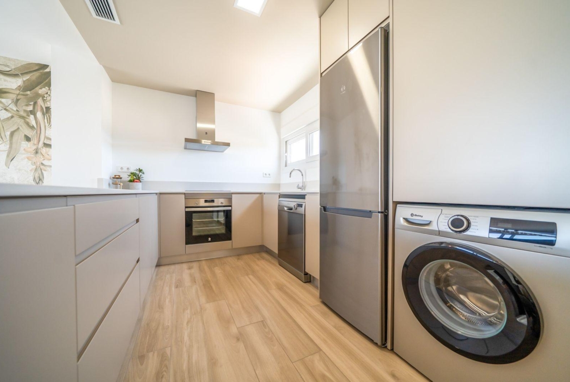 Bright modern kitchen with sleek appliances and wood-effect flooring in a 2 bedroom top floor bungalow at Vistabella Golf, Orihuela.