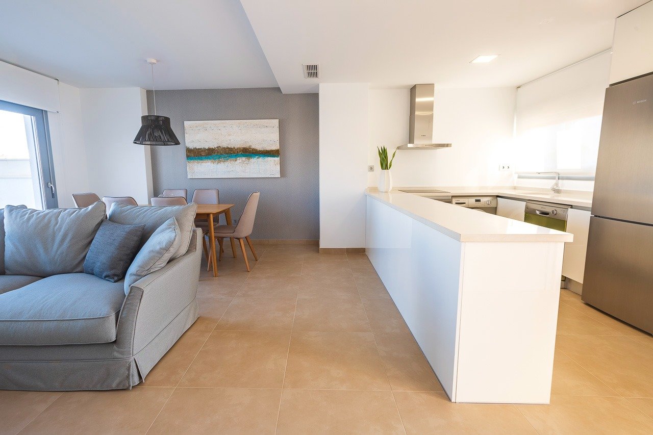 Bright open-plan living and sleek kitchen in a modern 2-bedroom top floor apartment with solarium in Vistabella Golf, Orihuela.