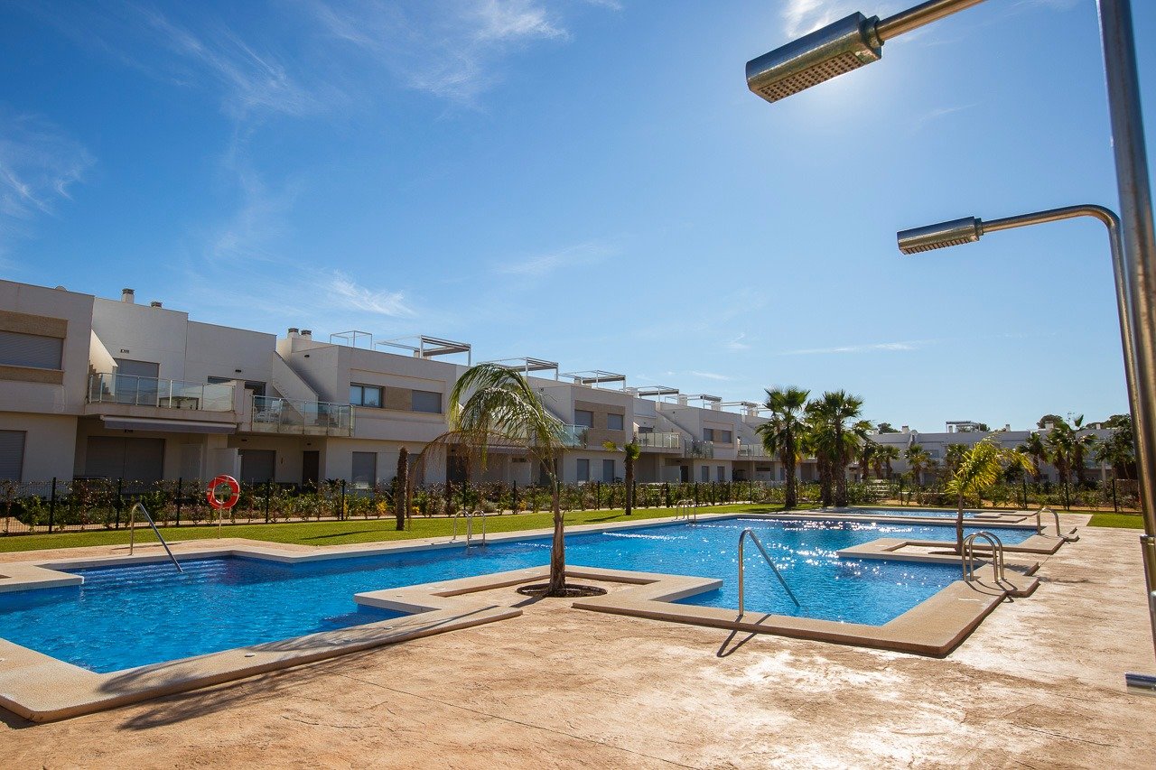 Sun-drenched communal pool with modern outdoor showers in front of luxury 2-bedroom top floor apartment in Vistabella Golf, Orihuela