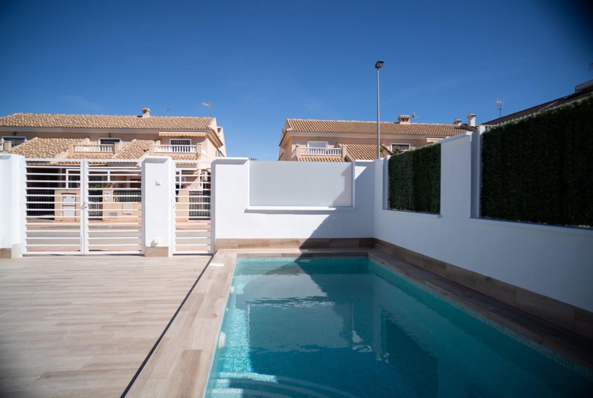NEW-BUILD-TOWNHOUSES-IN-SAN-JAVIER-1 Private turquoise swimming pool with modern tiled terrace and secure white fencing in new build townhouses in San Javier