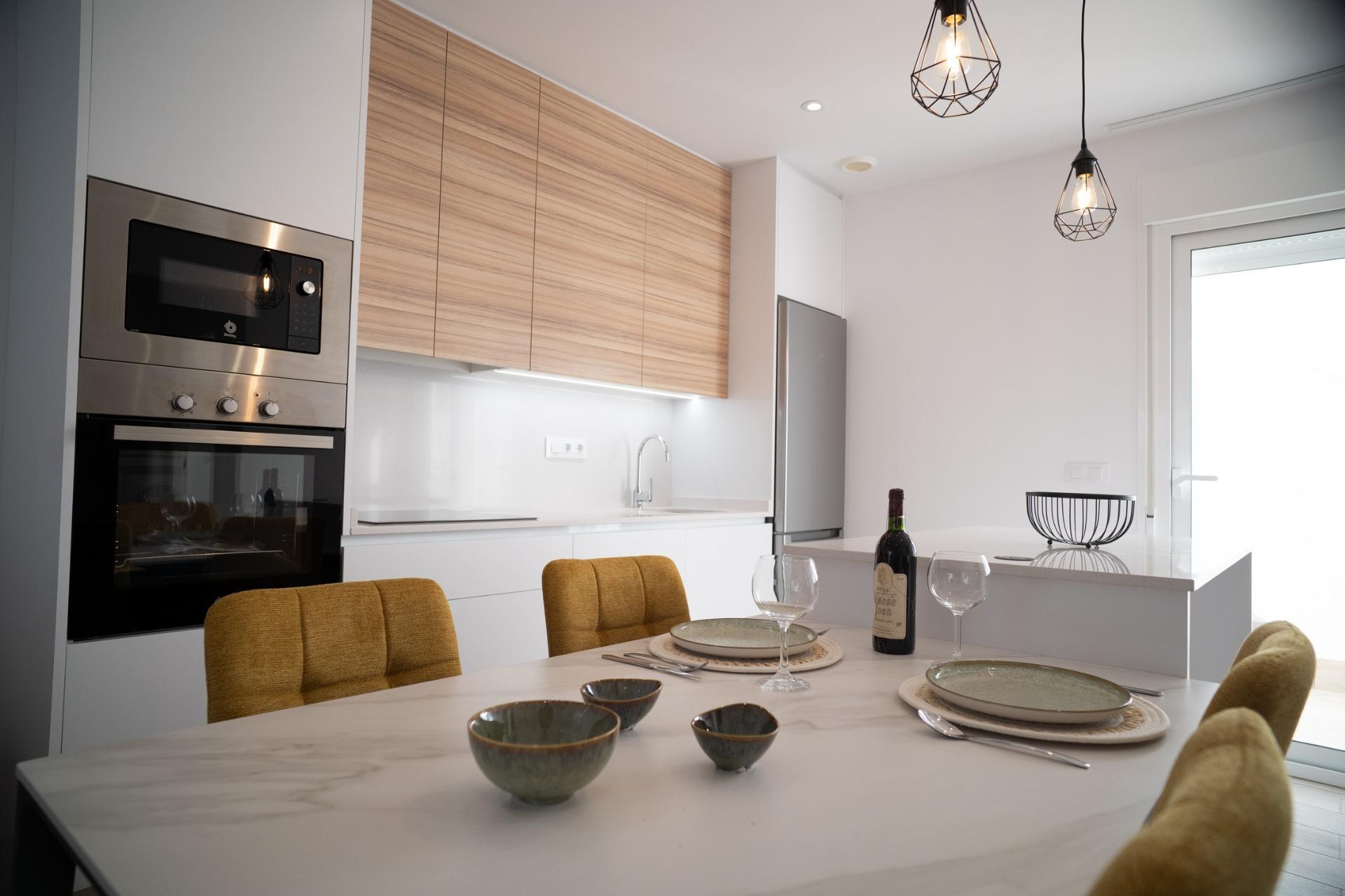 NEW-BUILD-TOWNHOUSES-IN-SAN-JAVIER-10 Modern bright kitchen with sleek appliances and elegant dining area in new build townhouses in San Javier
