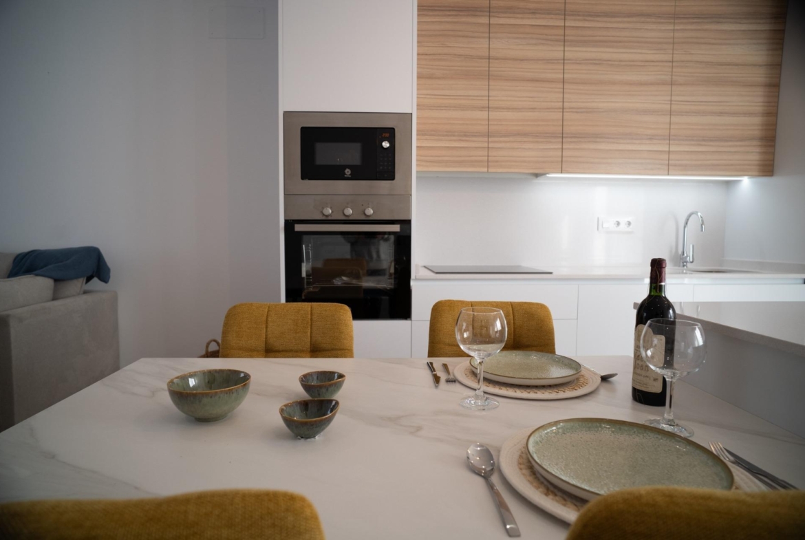 Bright, modern kitchen and dining area with sleek appliances and elegant table setting in new build townhouses in San Javier.