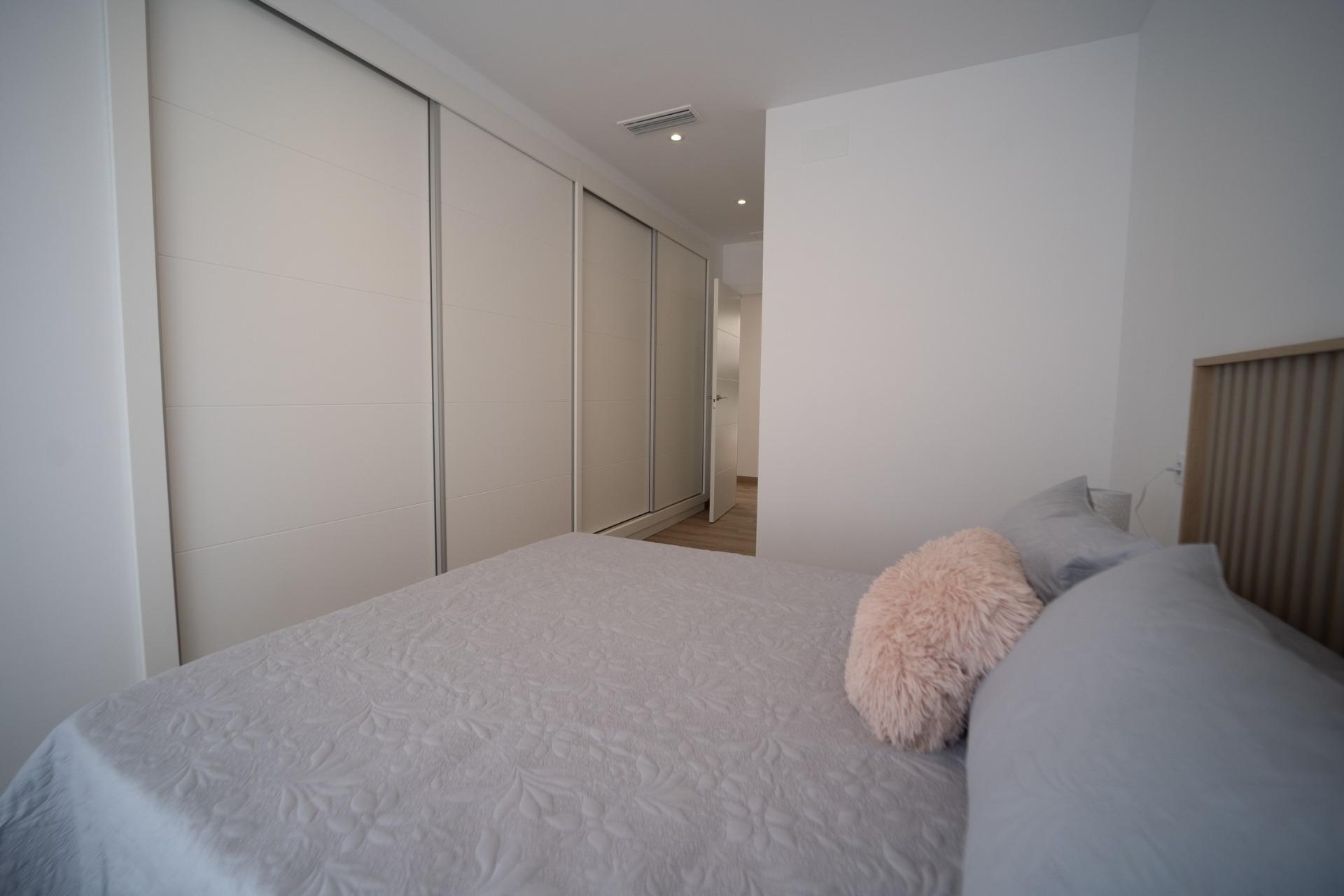 NEW-BUILD-TOWNHOUSES-IN-SAN-JAVIER-18 Bright, modern bedroom with spacious built-in wardrobes and soft linens in new build townhouses in San Javier.