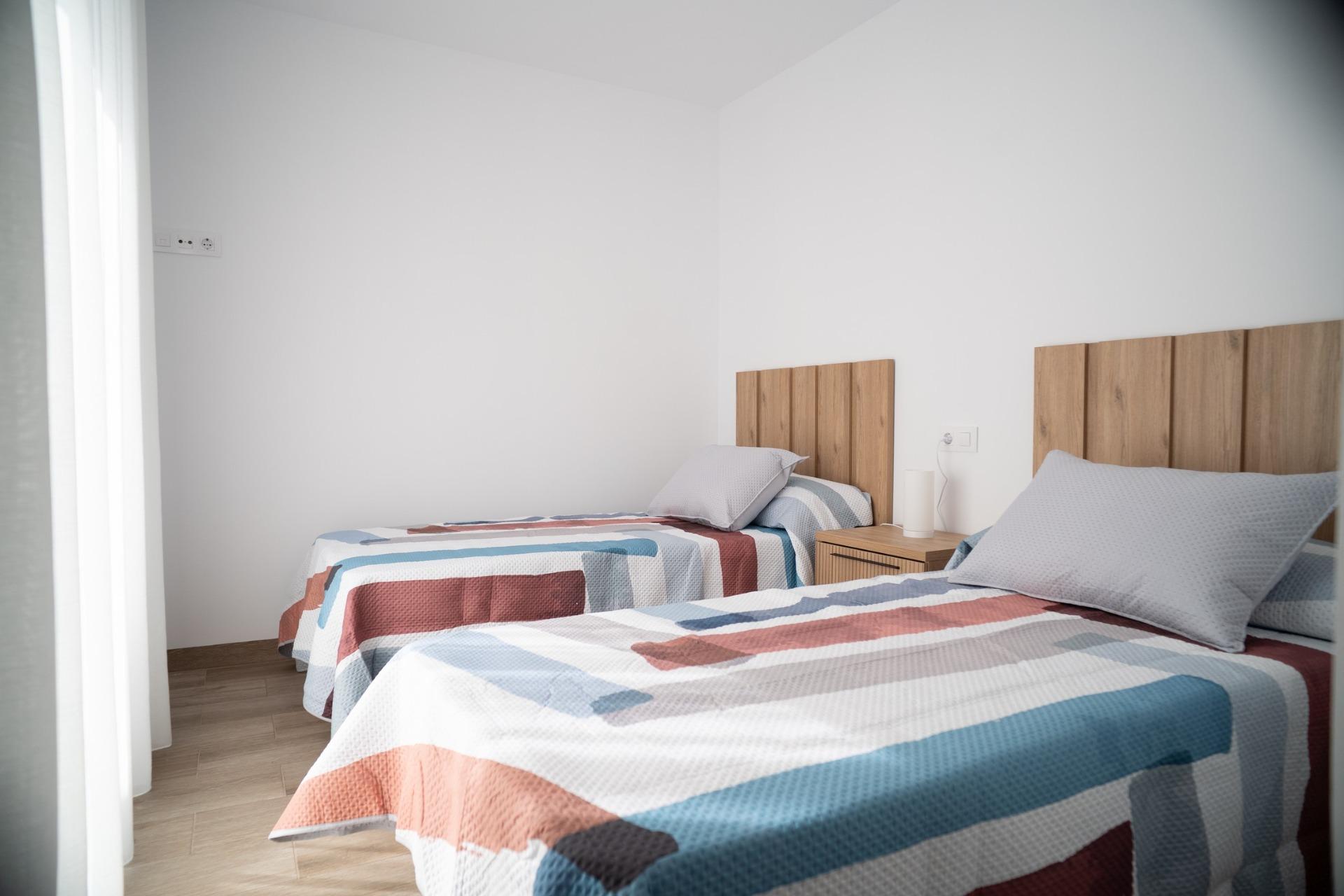 NEW-BUILD-TOWNHOUSES-IN-SAN-JAVIER-20 Bright and modern twin bedroom with wooden headboards and colorful bedding in new build townhouses in San Javier