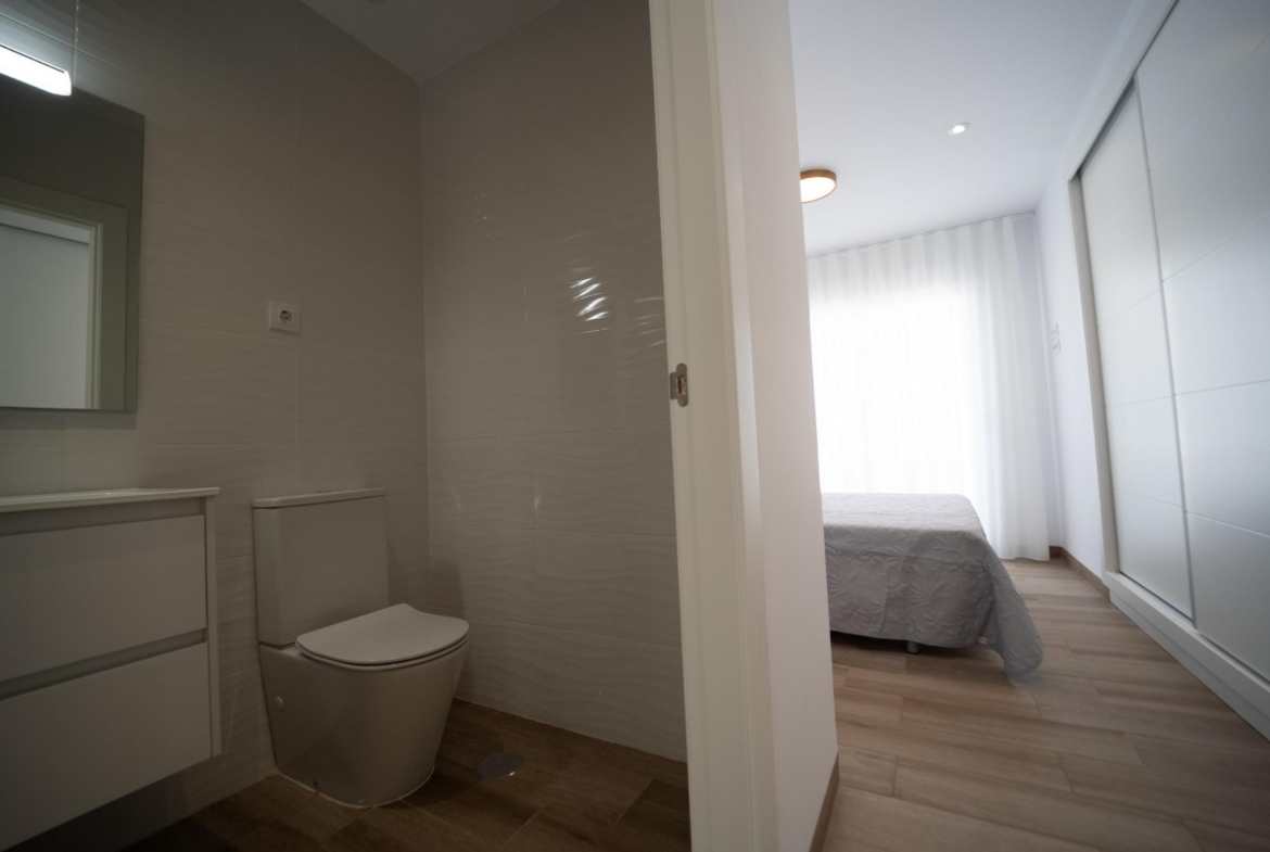 Modern townhouse bathroom with sleek fixtures and adjacent bright, serene bedroom in new San Javier development.