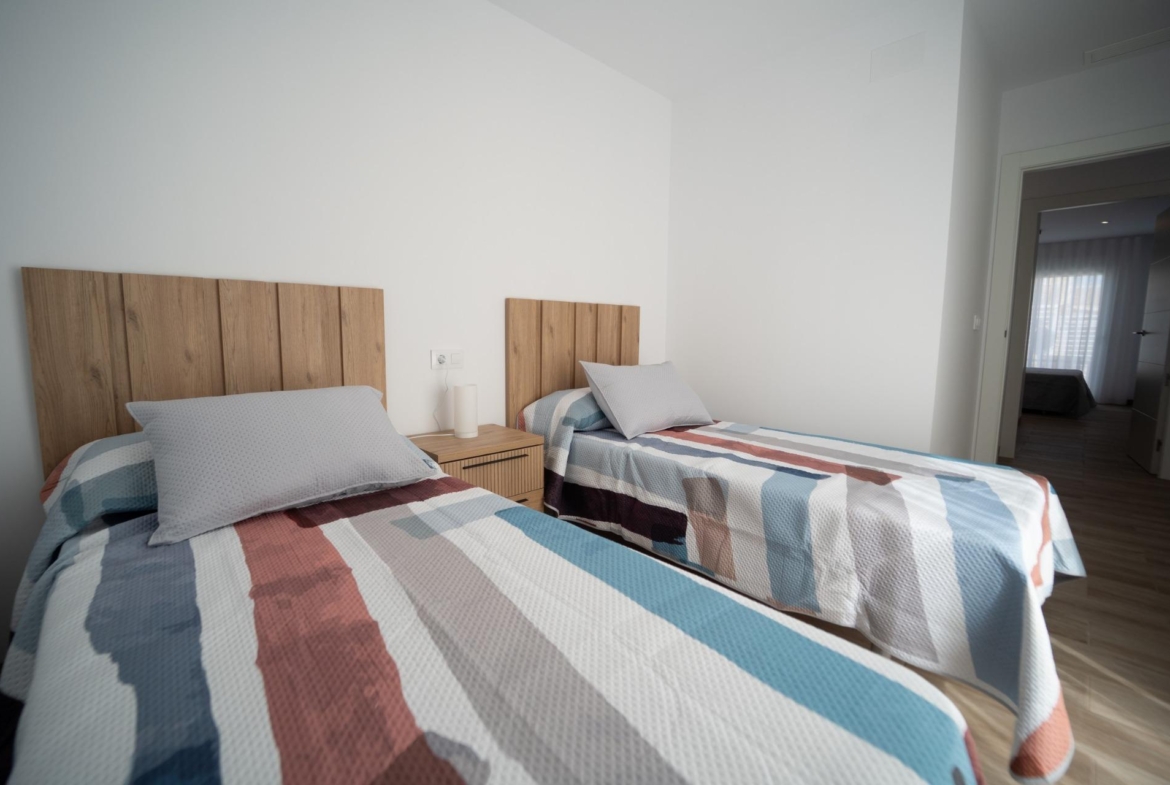 NEW-BUILD-TOWNHOUSES-IN-SAN-JAVIER-21 Bright twin bedroom with wooden headboards and colorful bedding in new build townhouses in San Javier