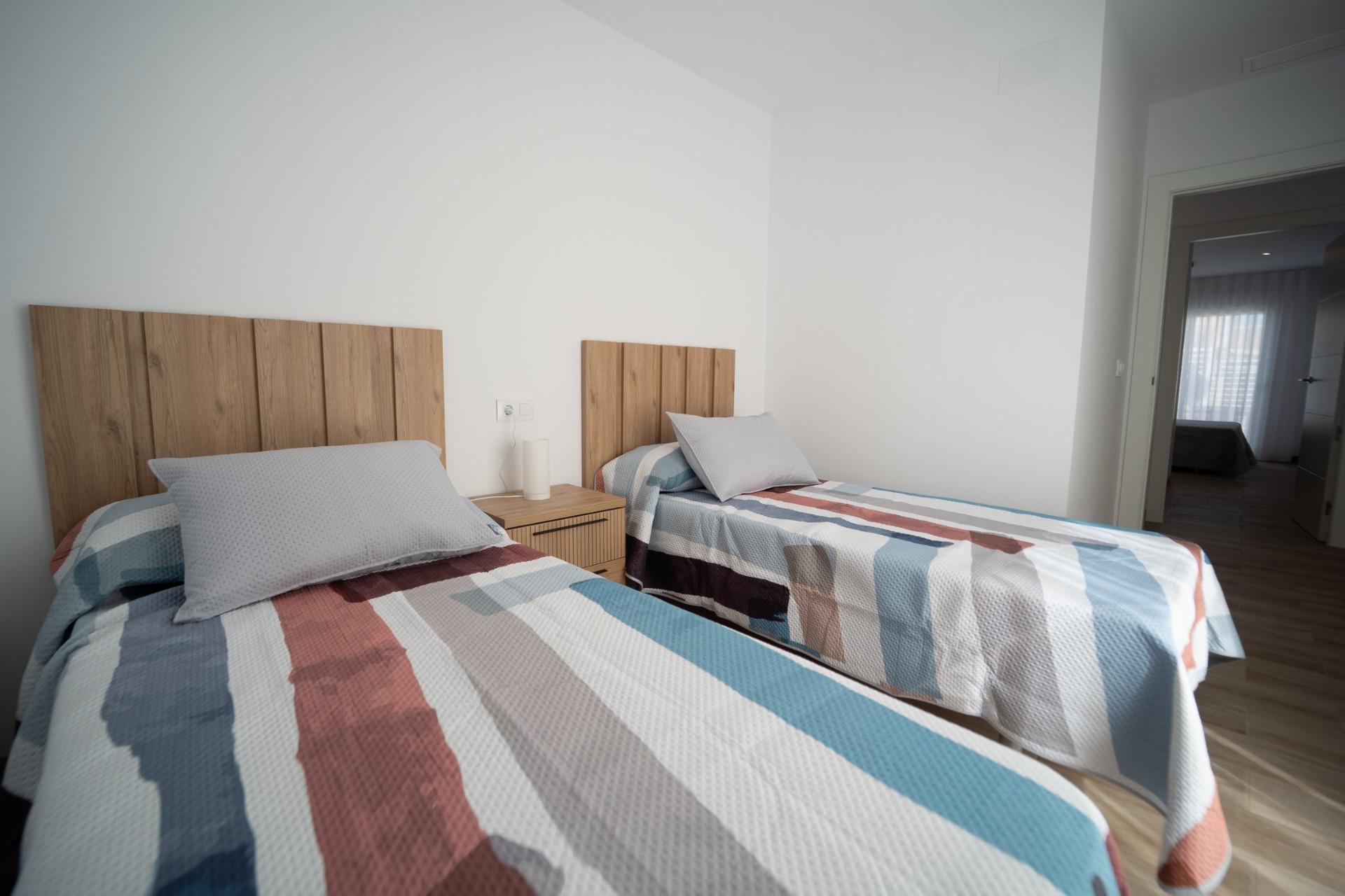 NEW-BUILD-TOWNHOUSES-IN-SAN-JAVIER-21 Bright twin bedroom with wooden headboards and colorful bedding in new build townhouses in San Javier