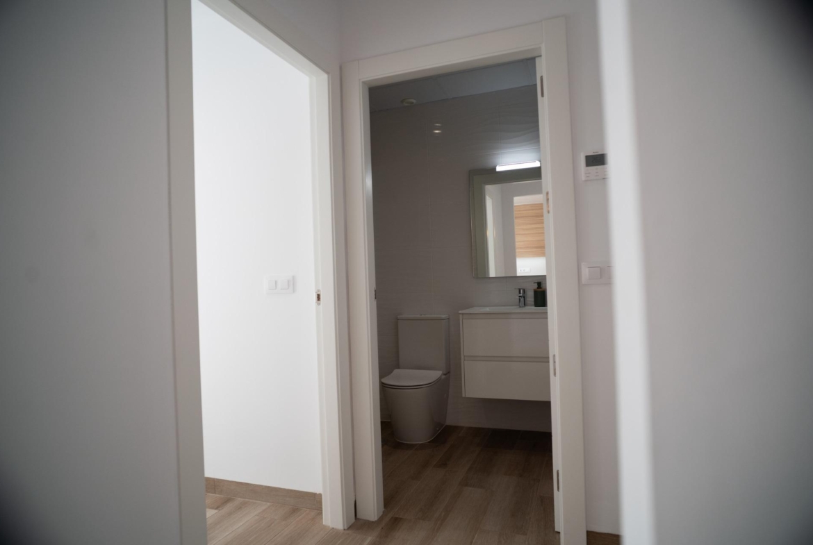 Bright modern bathroom with sleek fixtures and wood-effect flooring in new build townhouses in San Javier.