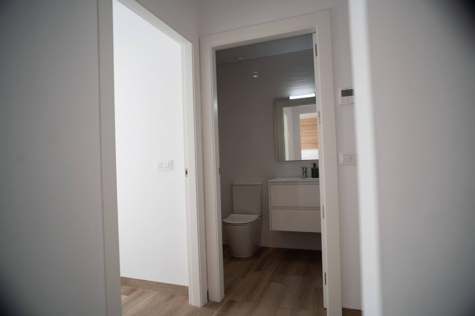 NEW-BUILD-TOWNHOUSES-IN-SAN-JAVIER-21 Bright modern bathroom with sleek fixtures and wood-effect flooring in new build townhouses in San Javier.