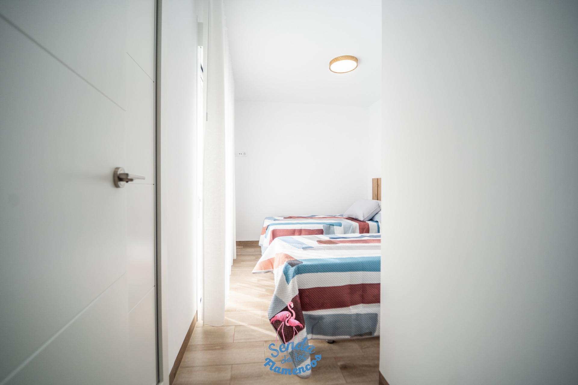 NEW-BUILD-TOWNHOUSES-IN-SAN-JAVIER-22 Bright, minimalist twin bedroom with colorful bedding in new build townhouses in San Javier showcasing clean modern design.