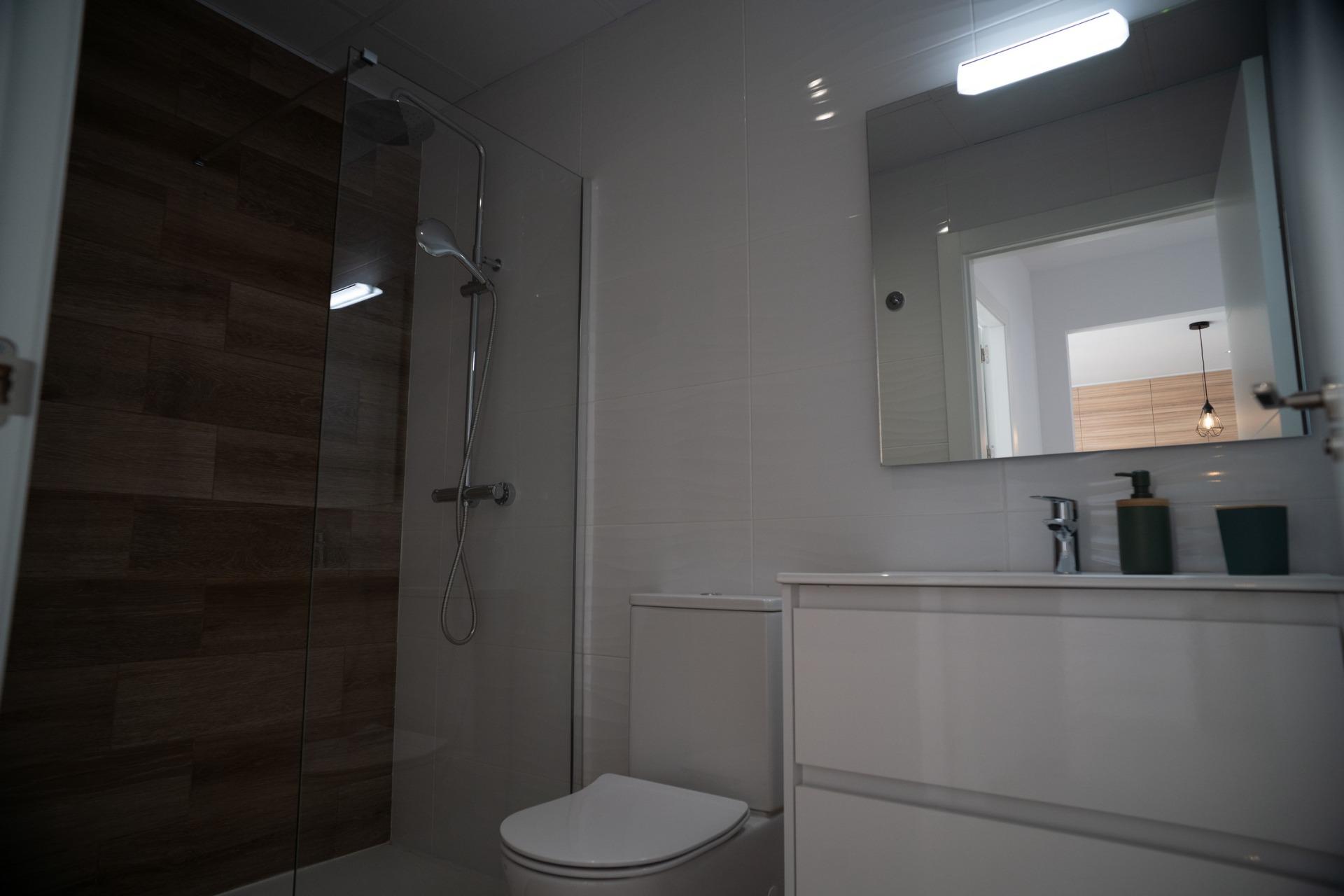 NEW-BUILD-TOWNHOUSES-IN-SAN-JAVIER-22 Modern bathroom with sleek wood-accented shower and bright vanity in luxury new build townhouses in San Javier