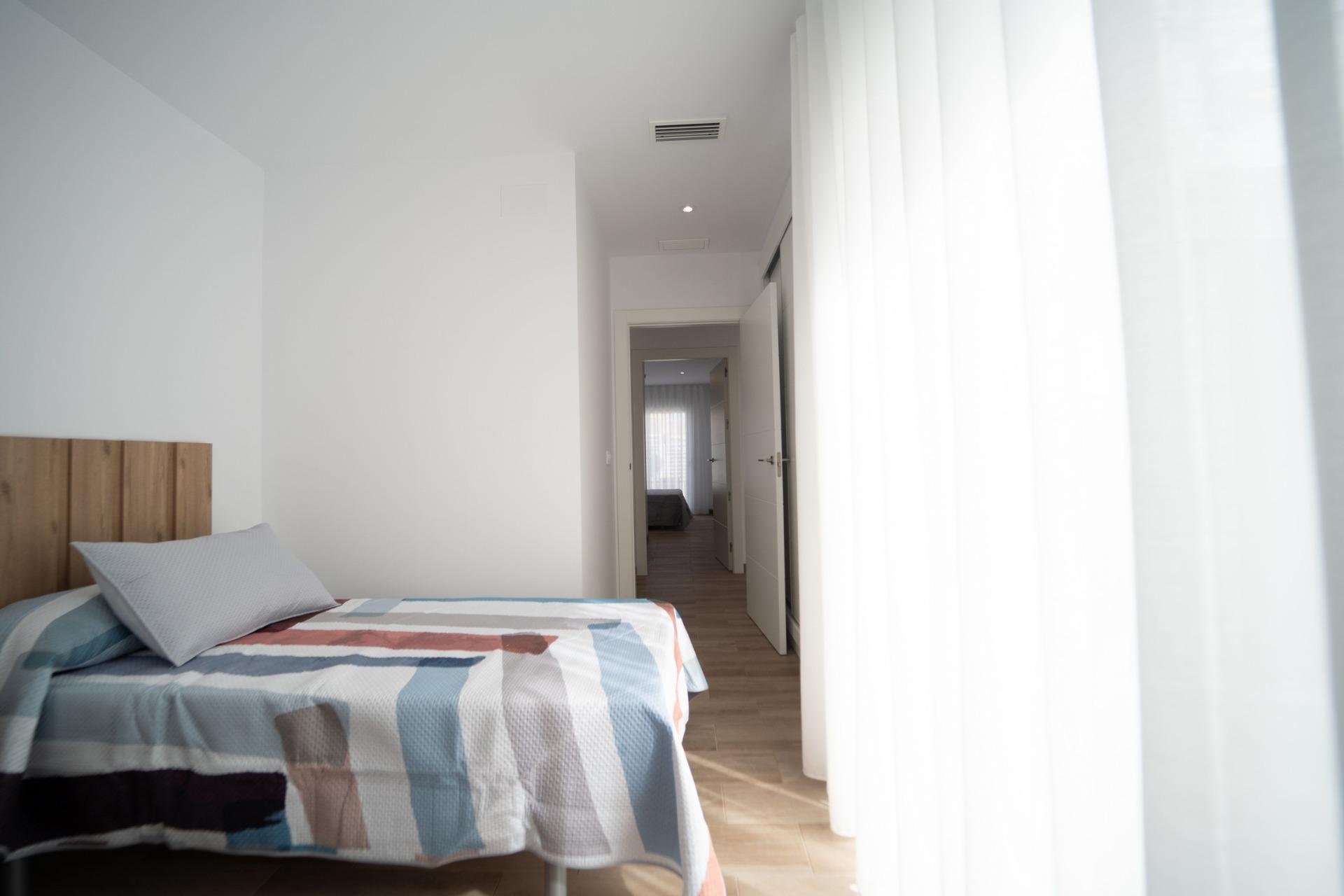 NEW-BUILD-TOWNHOUSES-IN-SAN-JAVIER-26 Bright modern bedroom with soft light and wood accents in new build townhouses in San Javier