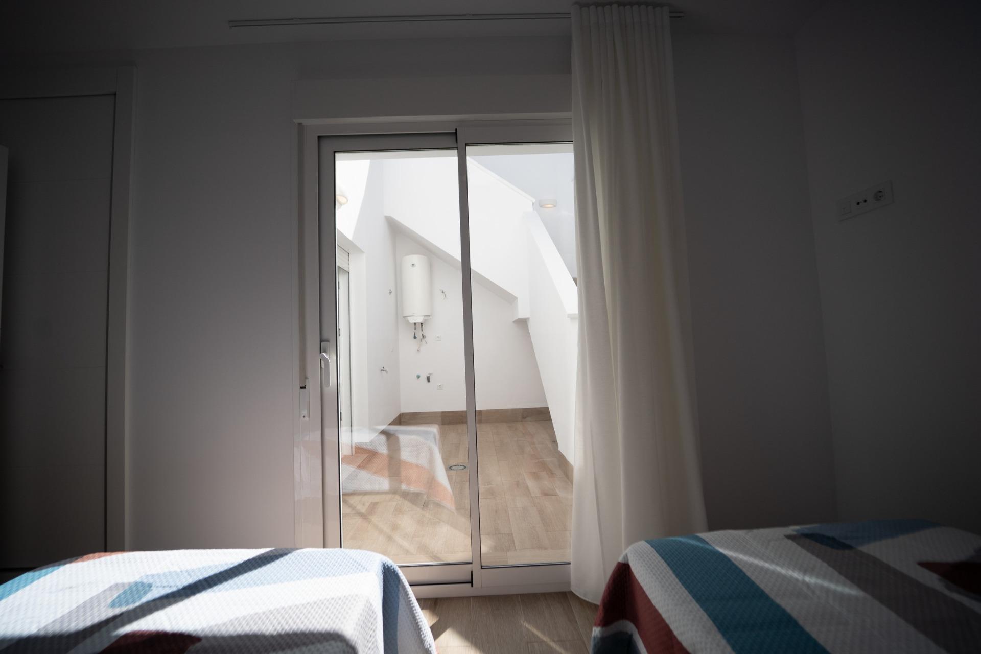NEW-BUILD-TOWNHOUSES-IN-SAN-JAVIER-27 Bright twin bedroom with sliding glass doors opening to a private sunlit terrace in modern new build townhouses in San Javier.