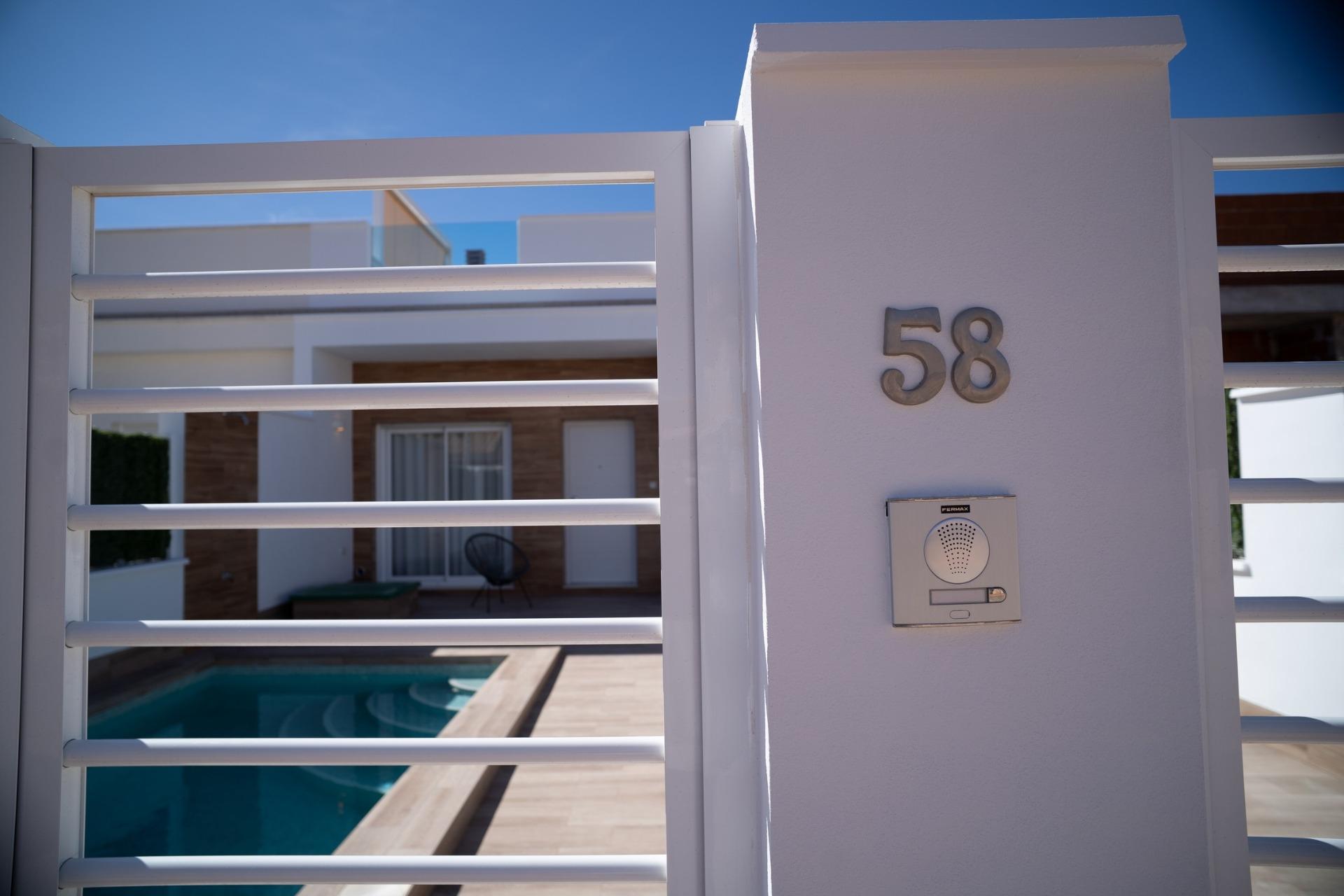 NEW-BUILD-TOWNHOUSES-IN-SAN-JAVIER-28 Modern new build townhouse in San Javier with private turquoise pool and sleek white gated exterior under clear blue sky