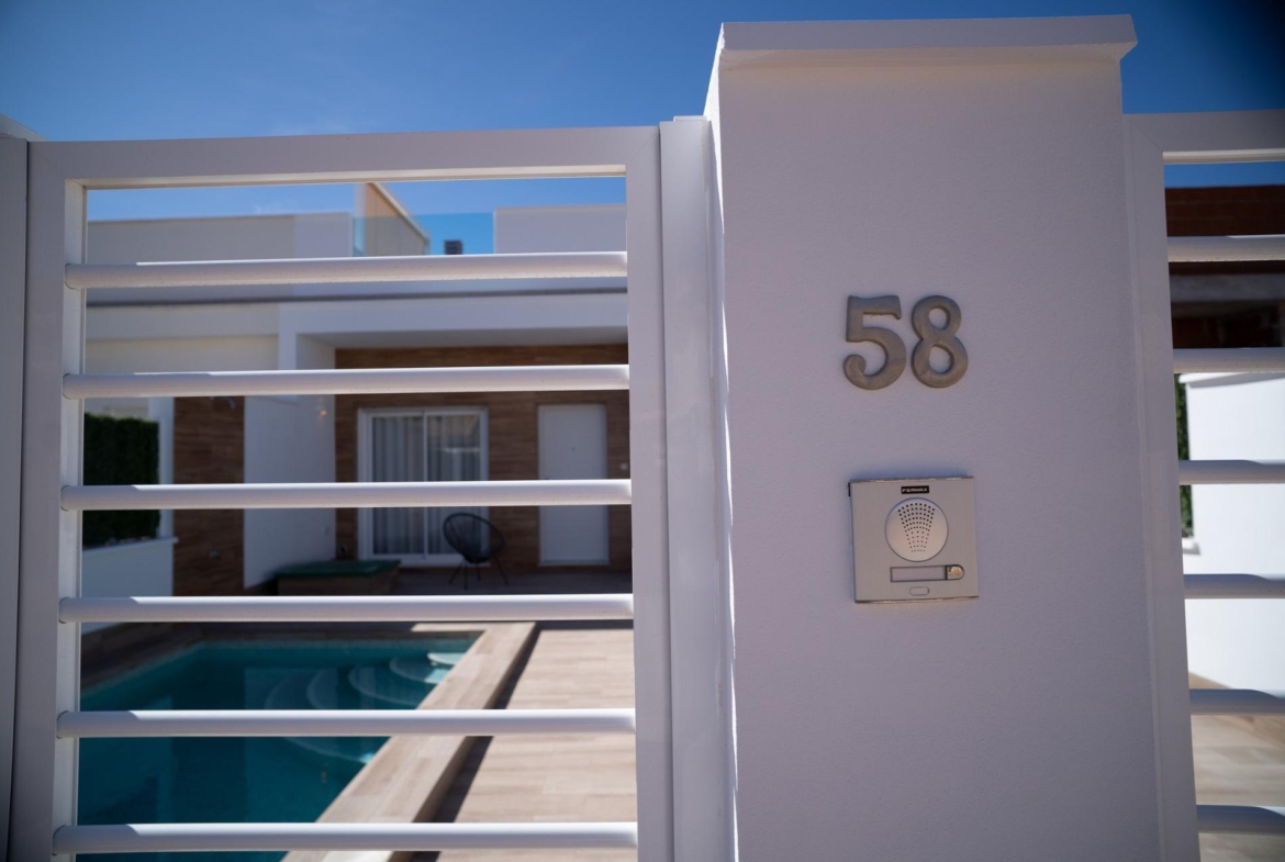 Modern white gated townhouse in San Javier featuring a private turquoise pool and serene outdoor lounge area