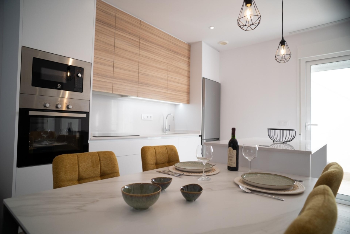 NEW-BUILD-TOWNHOUSES-IN-SAN-JAVIER-7 Modern, bright kitchen and dining area with sleek appliances and cozy seating in new build townhouses in San Javier