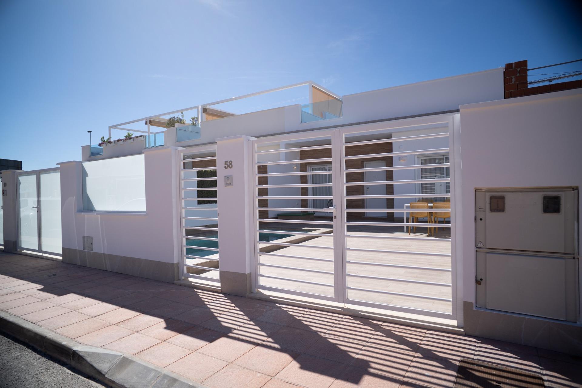 NEW-BUILD-TOWNHOUSES-IN-SAN-JAVIER-7 Modern white gated exterior with private terrace and pool at new build townhouses in San Javier under clear blue sky