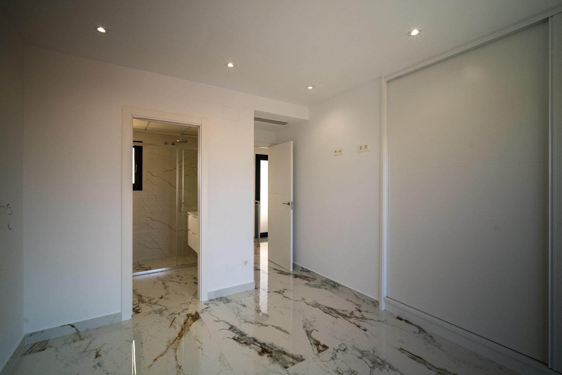 Bright modern bedroom with sleek marble flooring and minimalist design in a new 3-bedroom villa in La Nucia, Costa Blanca