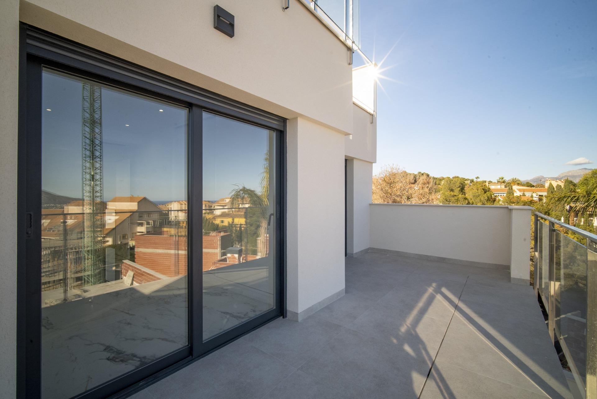 Spacious sunlit terrace with glass railing in modern 3-bedroom villa, La Nucia, offering serene outdoor living and panoramic views.