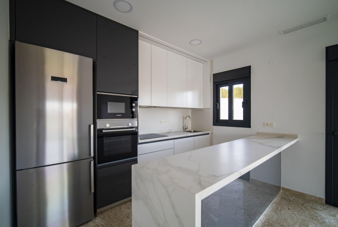 Sleek modern kitchen with marble island, stainless appliances, and bright windows in 3-bedroom villa in La Nucia, Costa Blanca