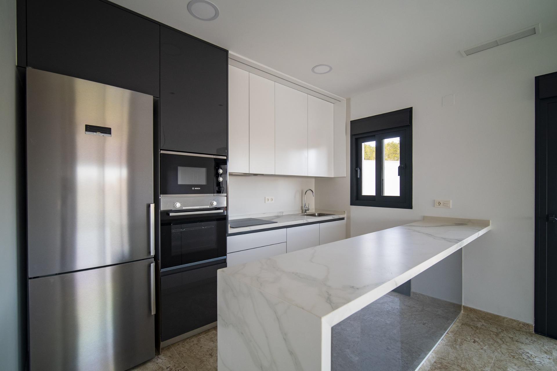 Sleek modern kitchen with marble island, stainless appliances, and bright windows in 3-bedroom villa in La Nucia, Costa Blanca