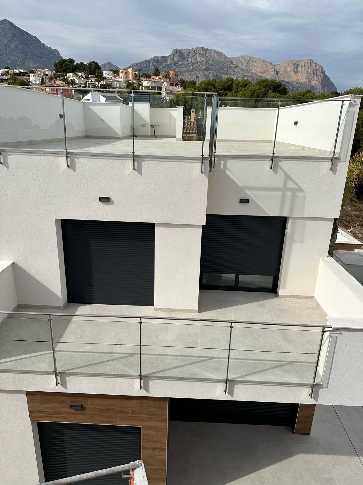 Bright, modern three-bedroom villa exterior in La Nucia, Costa Blanca featuring sleek glass balconies and mountain views.
