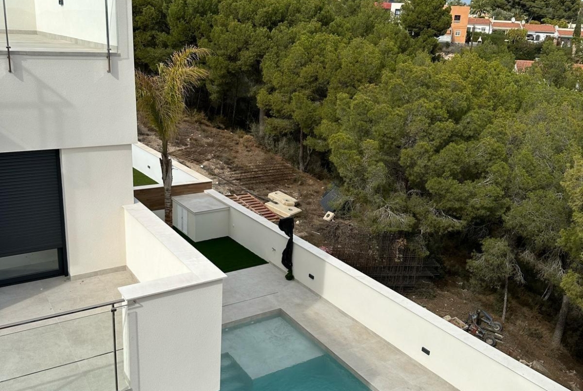 Sun-drenched modern 3-bedroom villa with private pool and sleek terrace overlooking lush greenery in La Nucia, Costa Blanca.