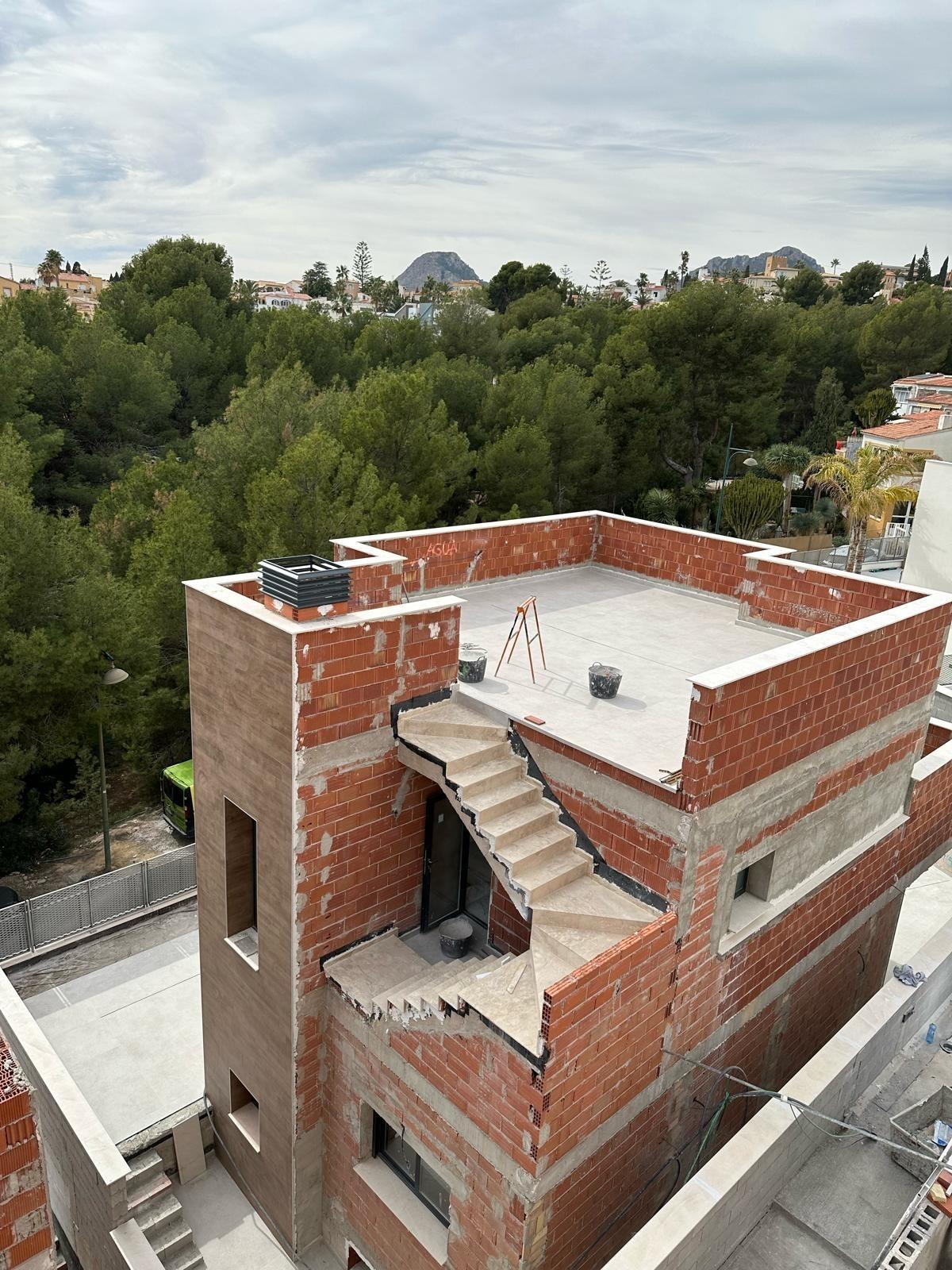 Unfinished modern 3-bedroom villa under construction with rooftop terrace in La Nucia, Costa Blanca, surrounded by lush greenery.