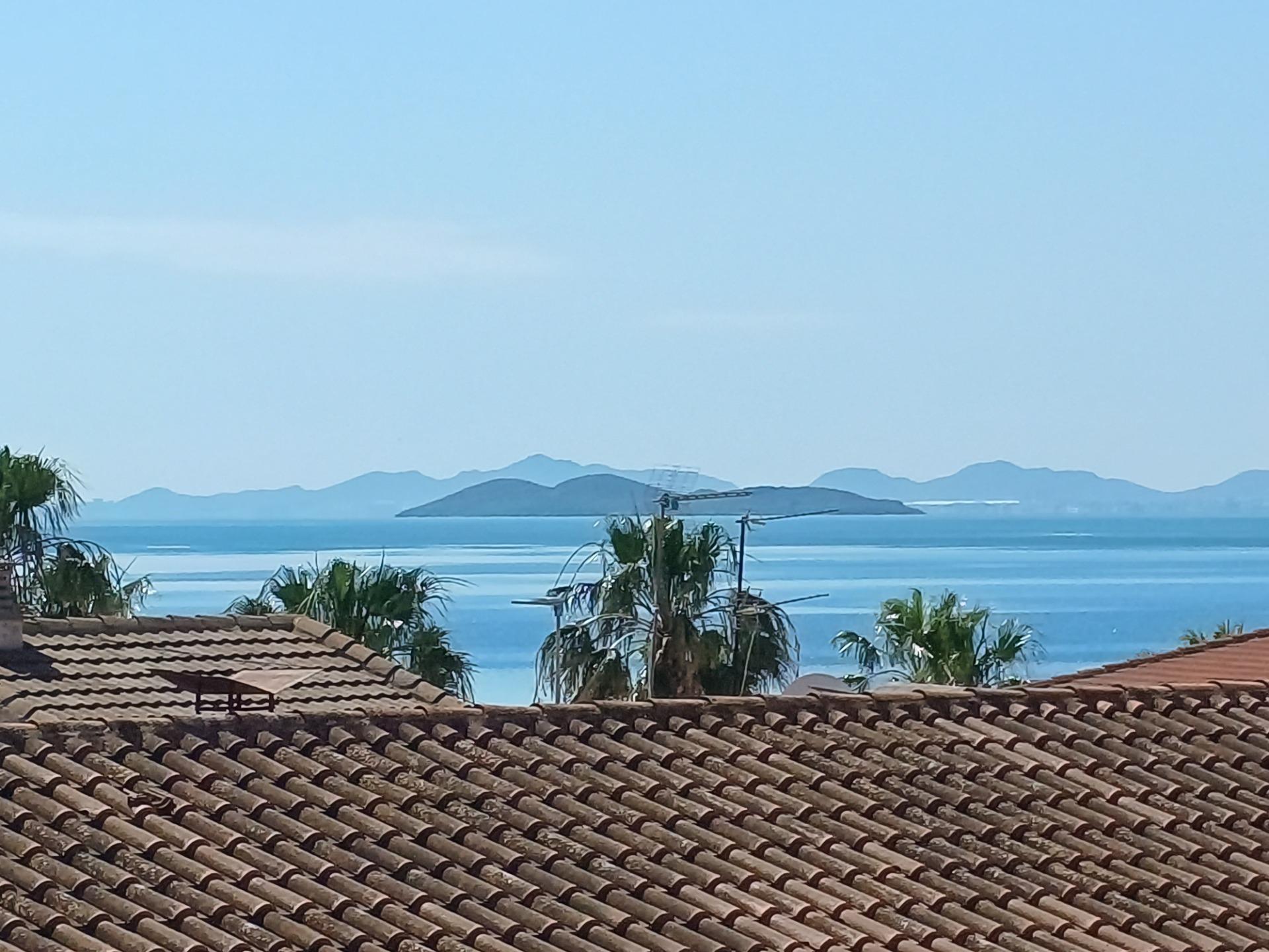 Panoramic sea view over tiled roofs and swaying palm trees at exclusive new build villas in Los Alcázares, Murcia.