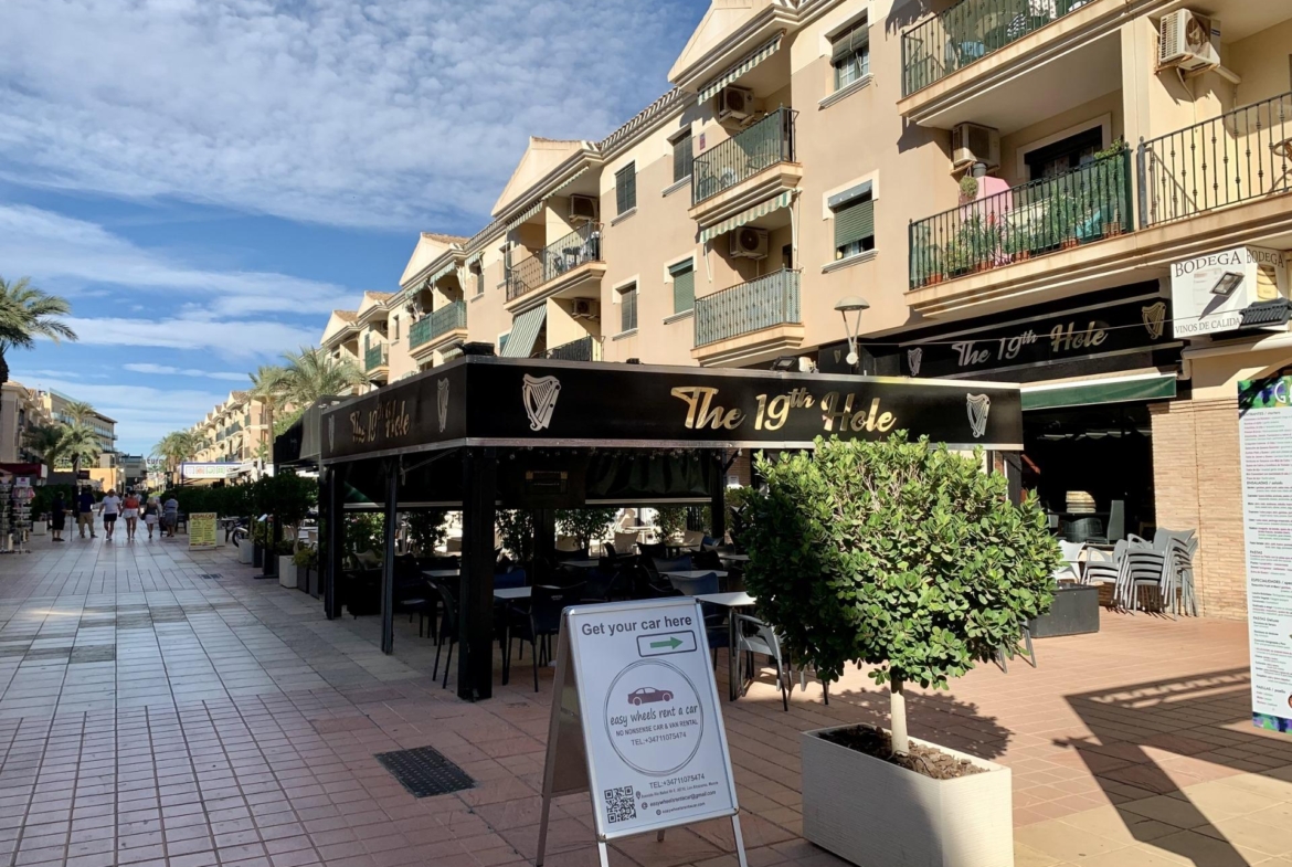 Vibrant sunlit street with elegant cafes and balconies in Los Alcázares, near exclusive new build villas with private pools.