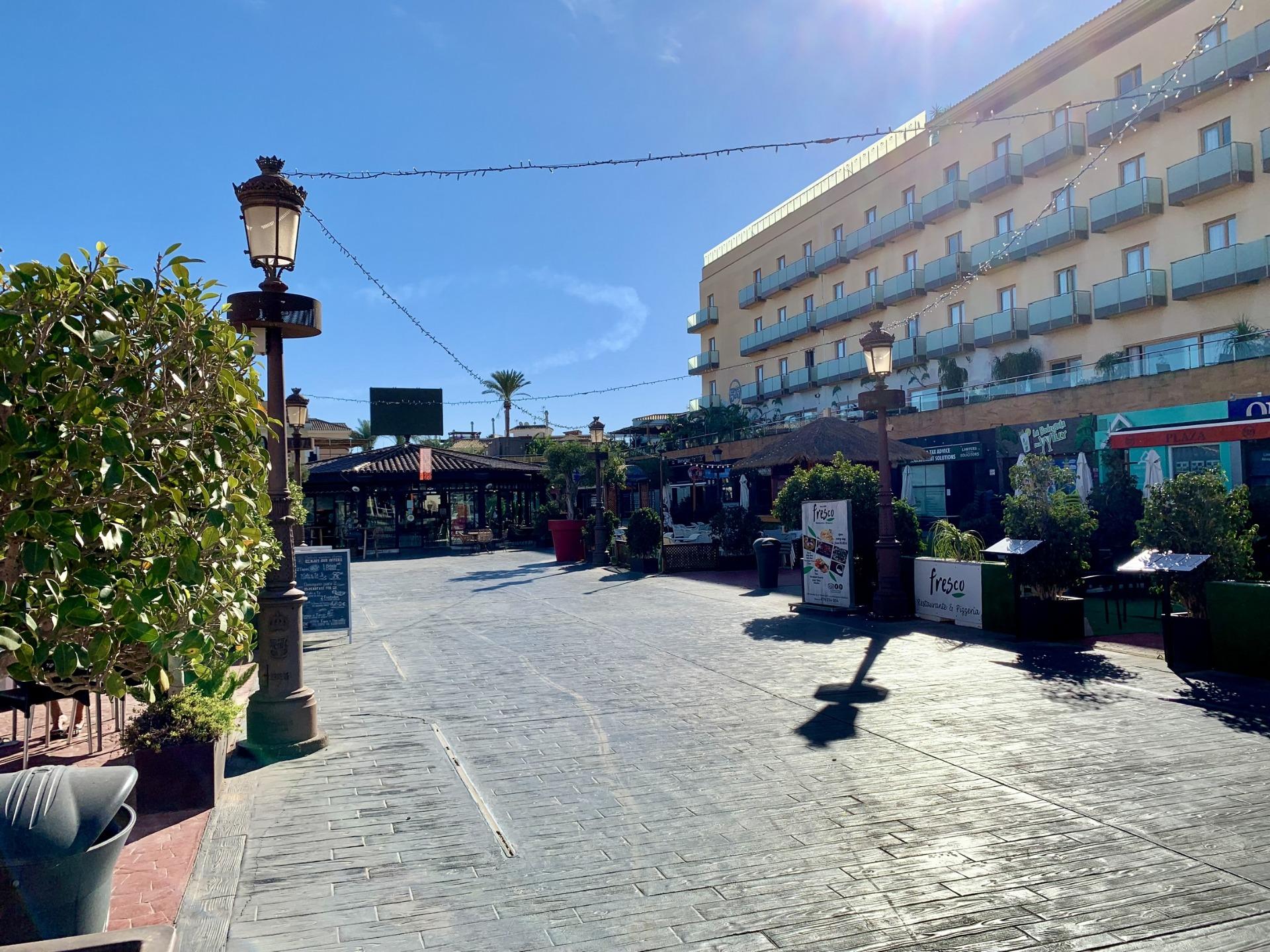 Bright sunlit street with charming cafes and modern buildings near exclusive new build villas in Los Alcázares, Murcia.