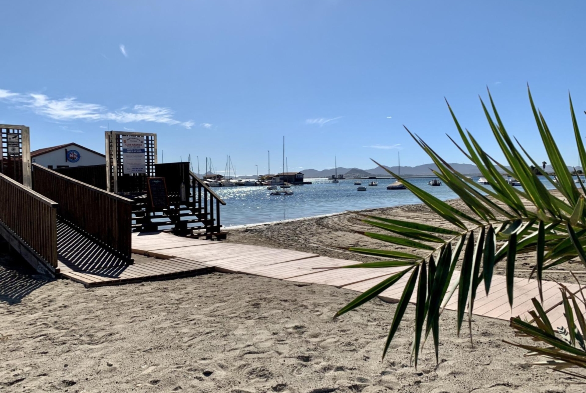 Sandy beach with clear blue sky and calm sea near exclusive new build villas in Los Alcázares, Murcia.